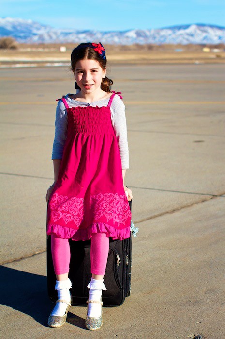Little girl in hot pink dress on airport tarmac : family travel and vacation.